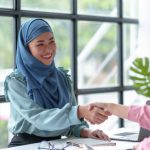 Beautiful Muslim Asian business woman shaking hands to promise to work together in a teamwork way.